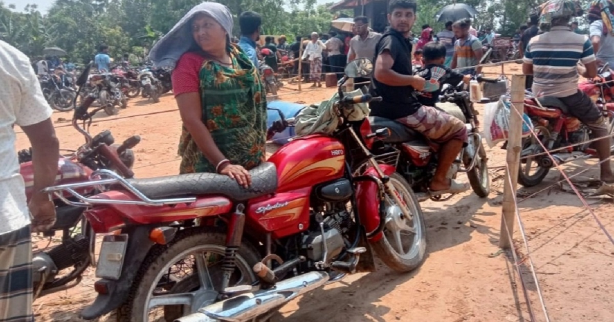 ছেলের মোটরসাইকেল চালানোর জন্য তেলের লাইনে দাঁড়িয়ে মা
